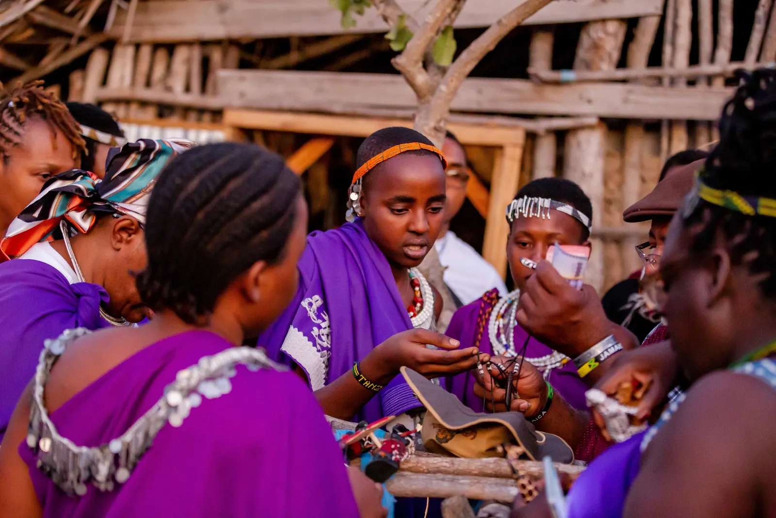 A group of women in purple shukas and beaded collars talking together