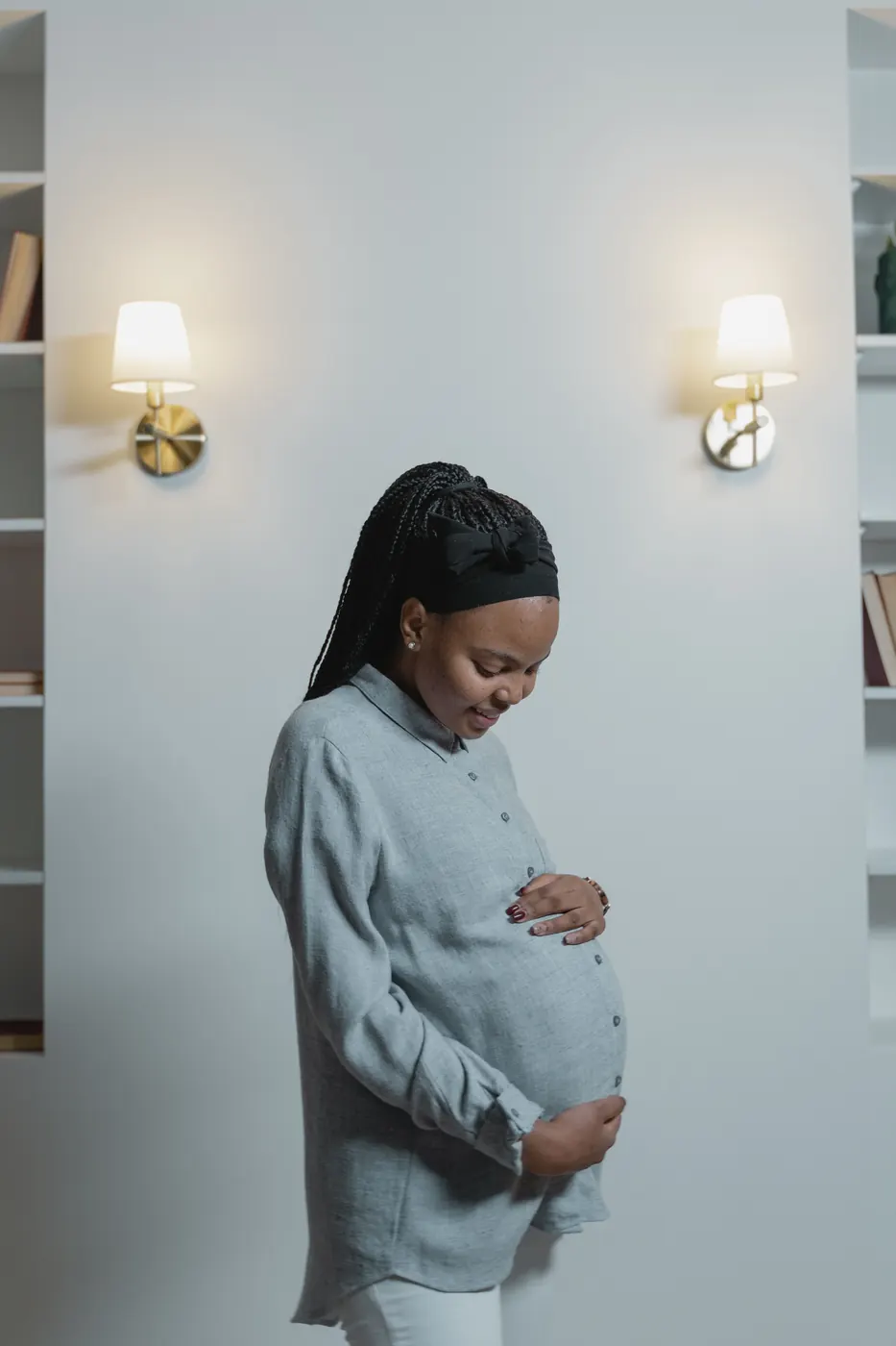 A pregnant woman standing with her hands on her belly