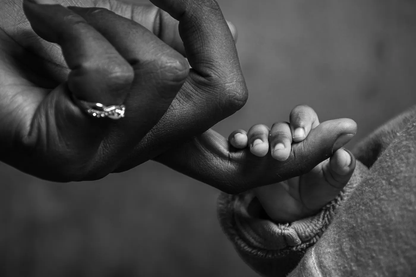 An adult hand holding a small child’s hand